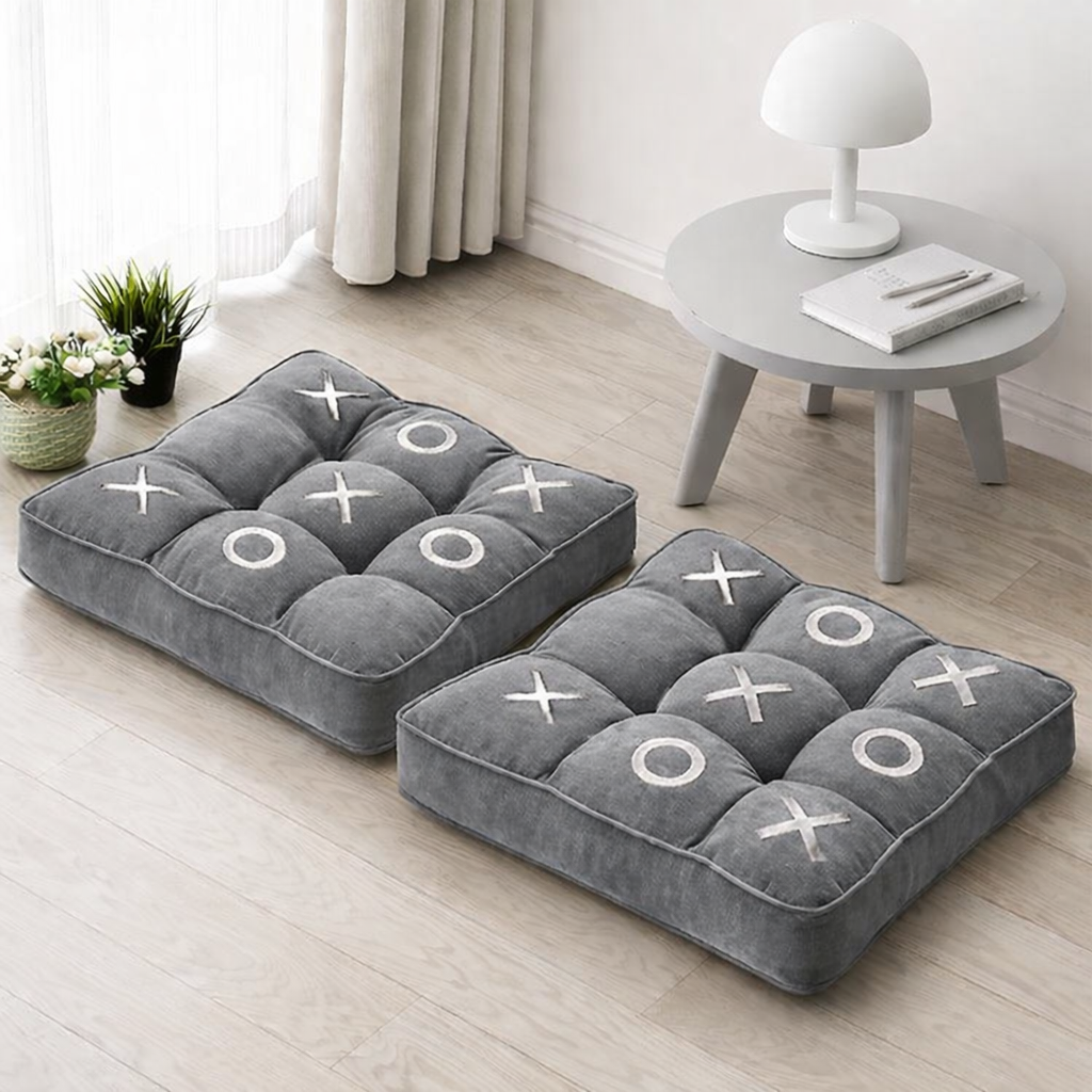 Grey floor cushions with subtle white embroidered X and O design in a modern interior setting