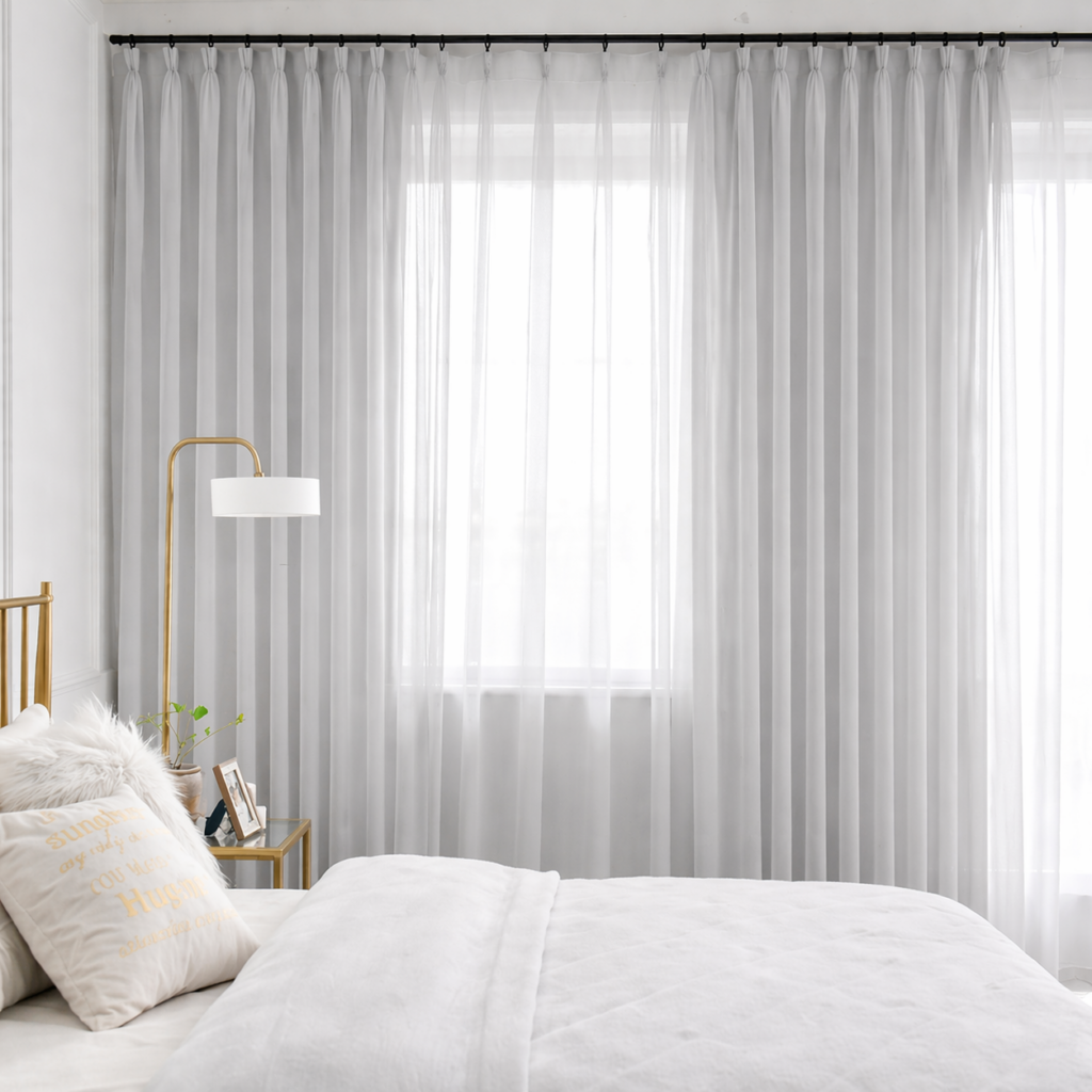 Soft light grey sheer curtains in a bright modern bedroom creating an airy and elegant window setting